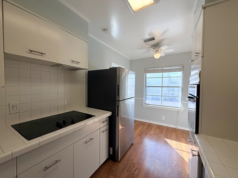 A kitchen with white cabinets and a black refrigerator.
