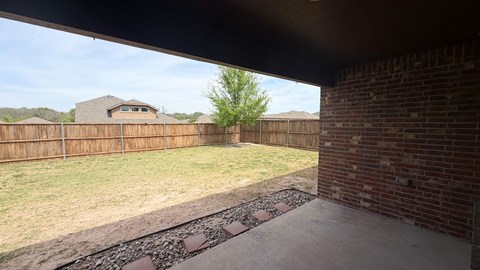 A backyard with a brick wall and a wooden fence.
