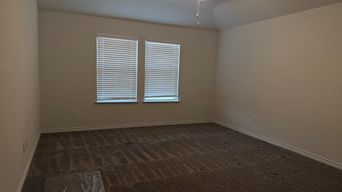 A room with a carpeted floor and a window with blinds.