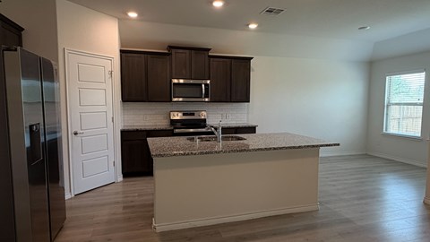 A kitchen with a granite countertop and a refrigerator.