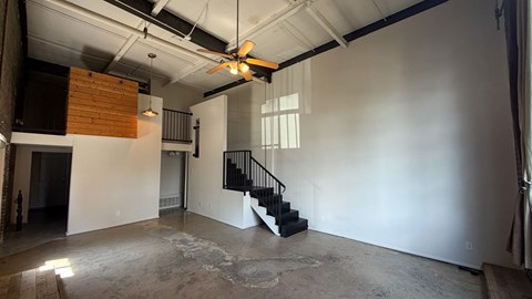 A room with a staircase and a ceiling fan.