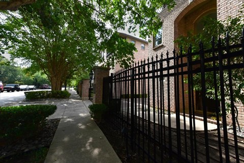 A black iron fence runs along the side of a sidewalk.
