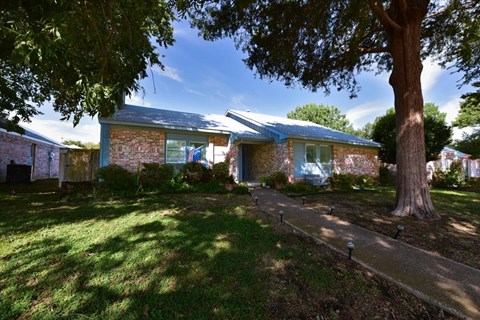 A house with a blue roof and a tree in front.