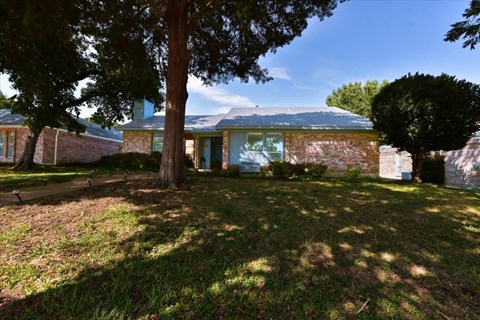 A house with a blue door and windows is surrounded by trees.