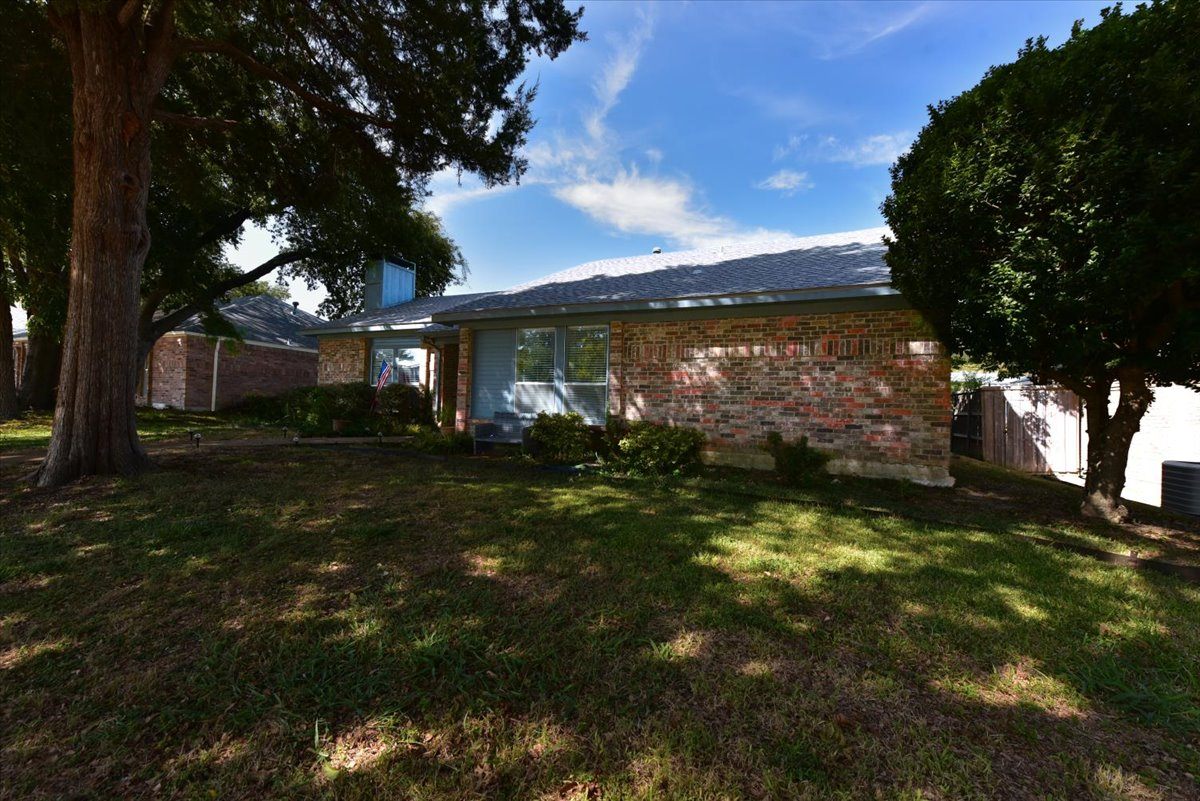 A house with a lawn and trees in front of it.