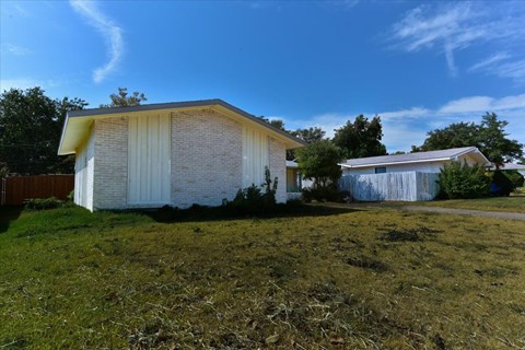 A white house with a yellow roof is surrounded by a grassy area.