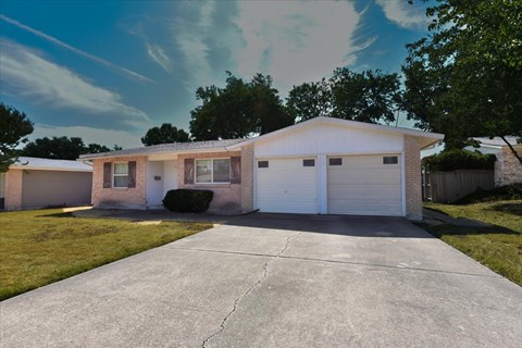 A house with a white garage door is in front of a tree.