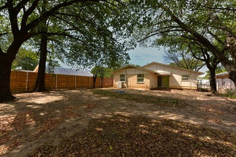 A house is surrounded by trees and a fence.