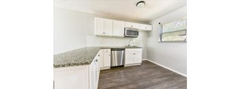 A kitchen with white cabinets and a granite countertop.