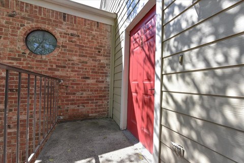 A red door is on the right side of a brick wall.