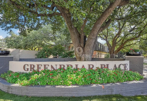 A sign that says Greenbriar Place is surrounded by flowers and greenery.