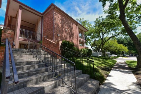 A red brick building with a metal railing on the stairs.