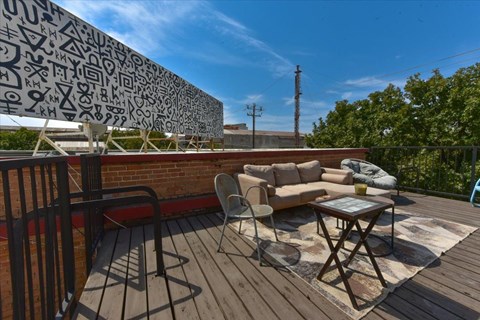 A patio with a table and chairs is set up on a wooden deck.