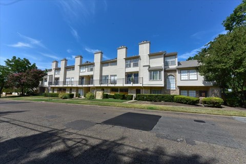 A large apartment building with a parking lot in front.