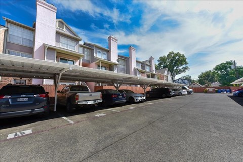 A parking lot with cars parked in front of apartment buildings.