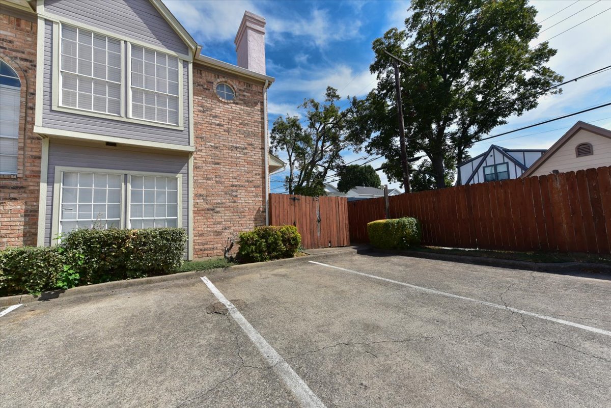 A brick house with a white window and a brown fence.