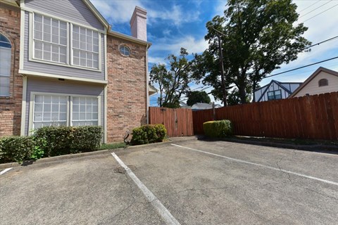 A brick house with a white window and a brown fence.