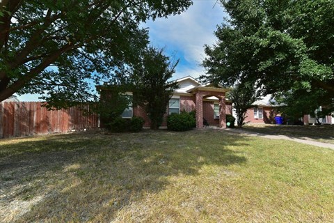 A house with a red fence and green trees in front.