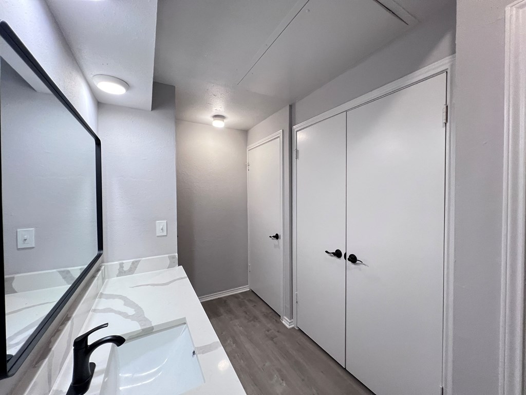 A bathroom with a sink, mirror, and cabinets.