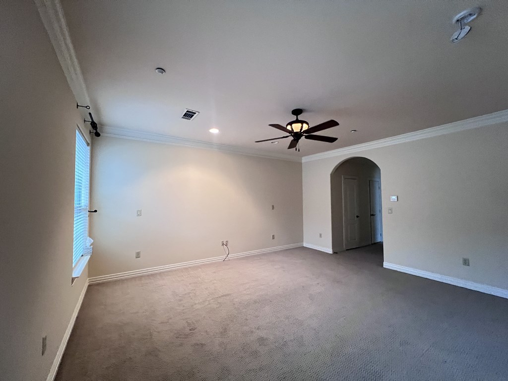 A room with a ceiling fan and carpeted floor.