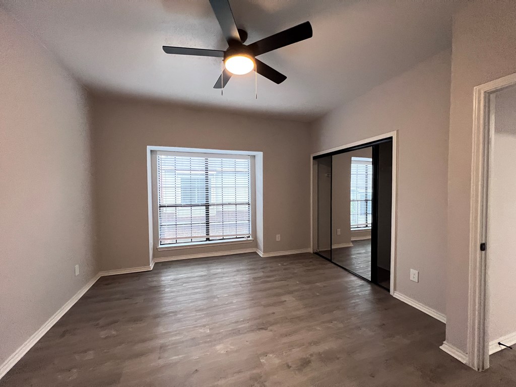 A room with a ceiling fan and a window with blinds.