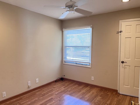 A room with a ceiling fan and a door.