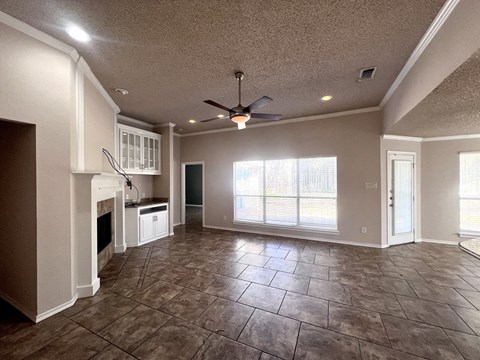 A spacious living room with a fireplace and a ceiling fan.
