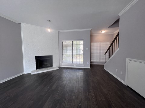 A living room with a fireplace and wooden floors.