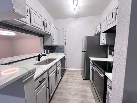 A kitchen with a sink, stove, and oven.