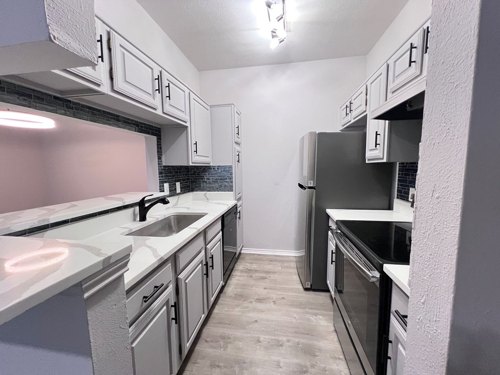 A kitchen with a sink, stove, and oven.