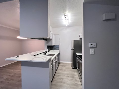 A kitchen with a white counter top and a refrigerator.