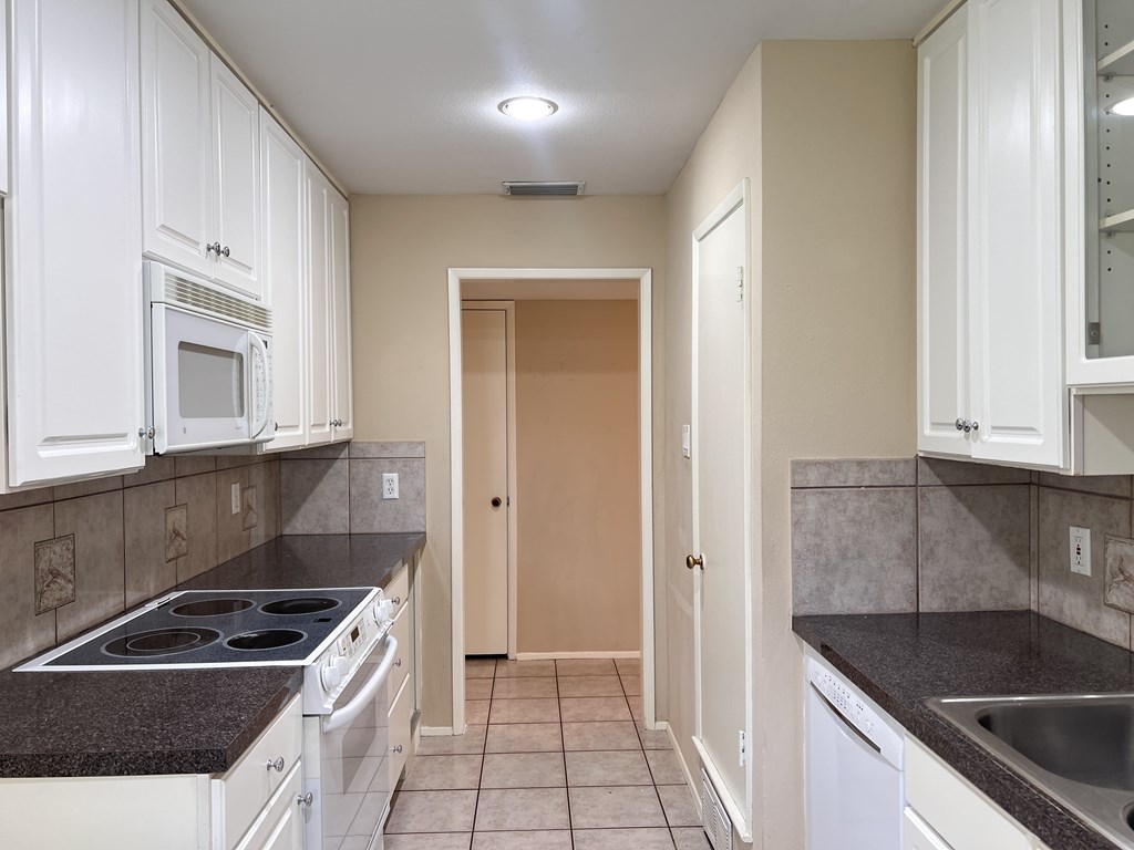 A kitchen with brown cabinets and a black counter top.