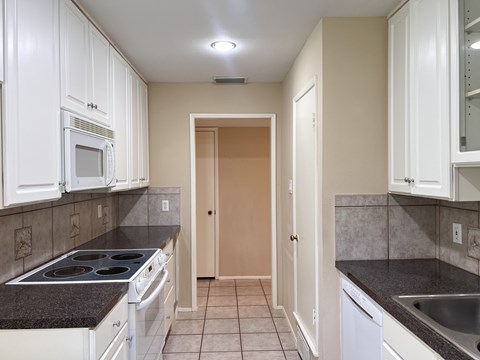 A kitchen with white cabinets and a black countertop.