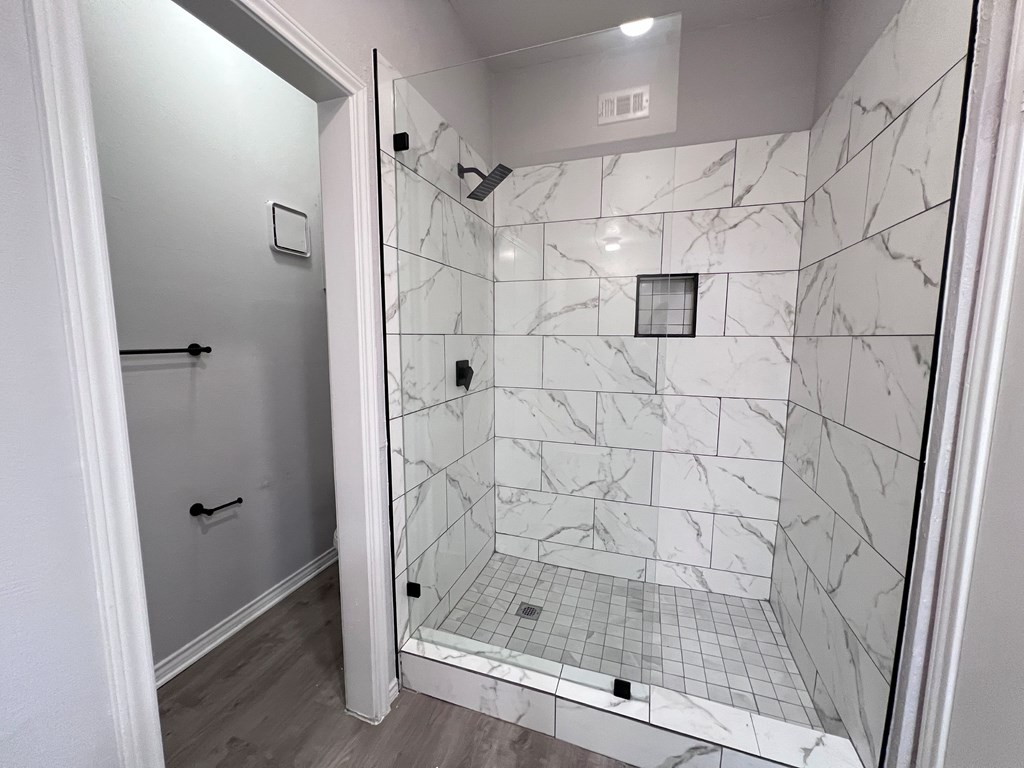 A white tiled shower with a glass door.