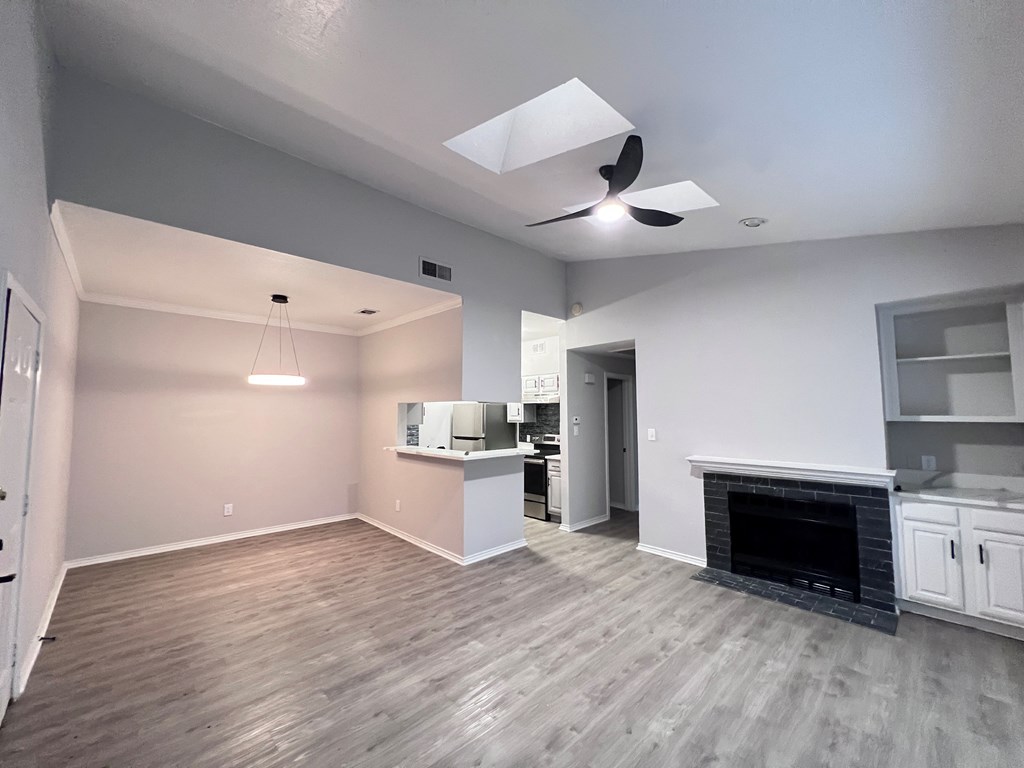 A spacious living room with a fireplace and a kitchen area in the background.