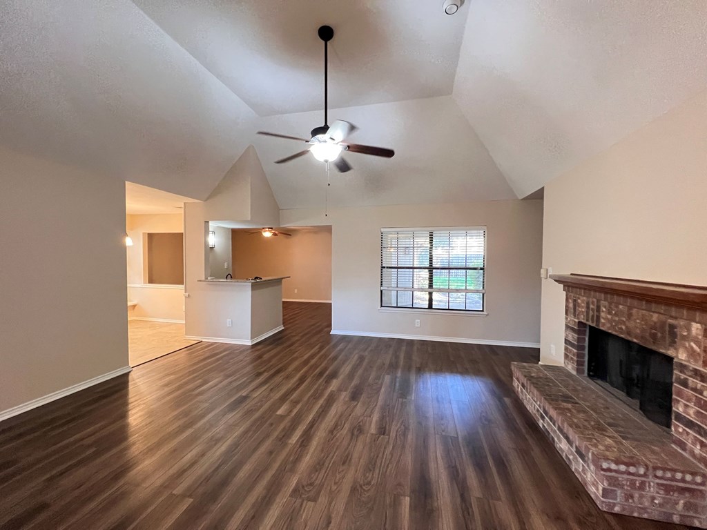 A living room with a fireplace and a ceiling fan.