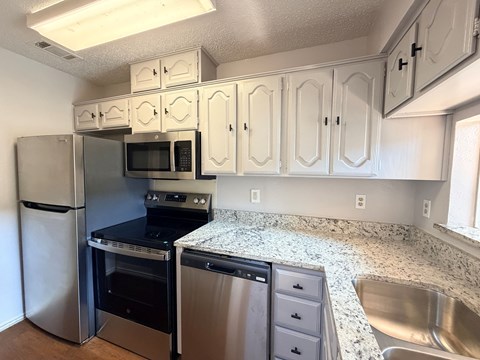A kitchen with white cabinets and stainless steel appliances.