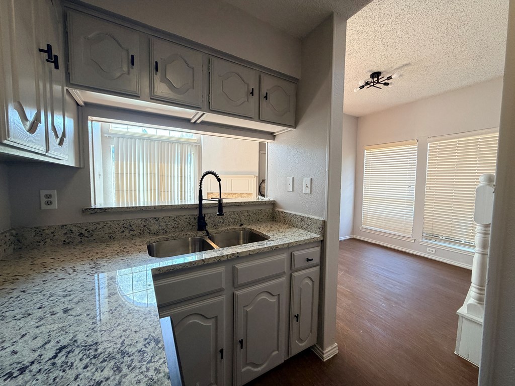 A kitchen with a marble countertop and white cabinets.