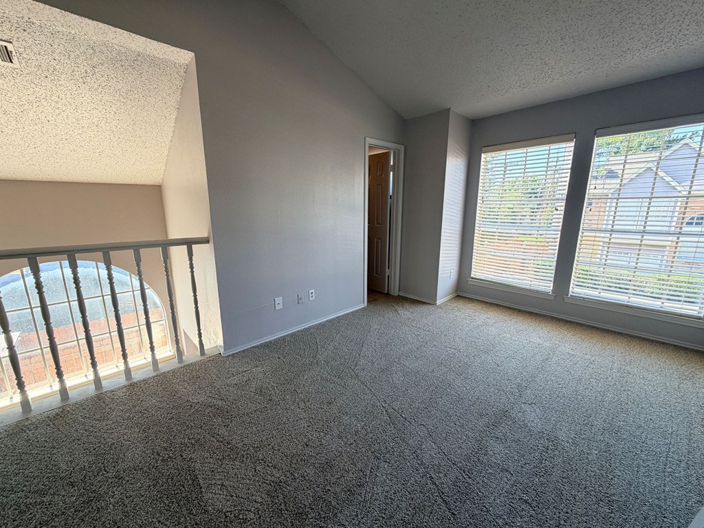 A room with a carpeted floor, a door, and a window with blinds.