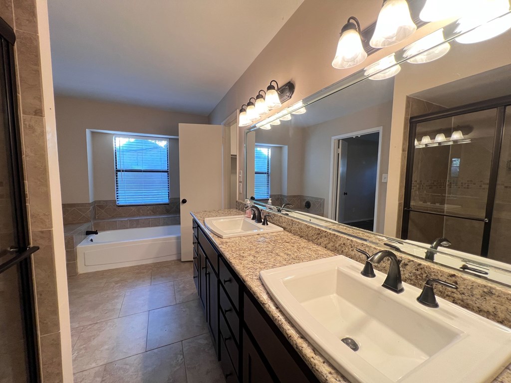 A bathroom with a white sink and a large mirror.