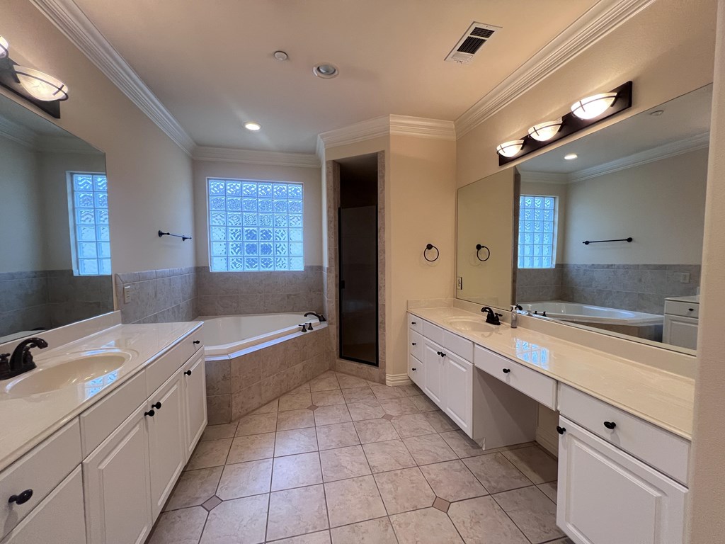 A large, well-lit bathroom with a bathtub, double sinks, and a large mirror.