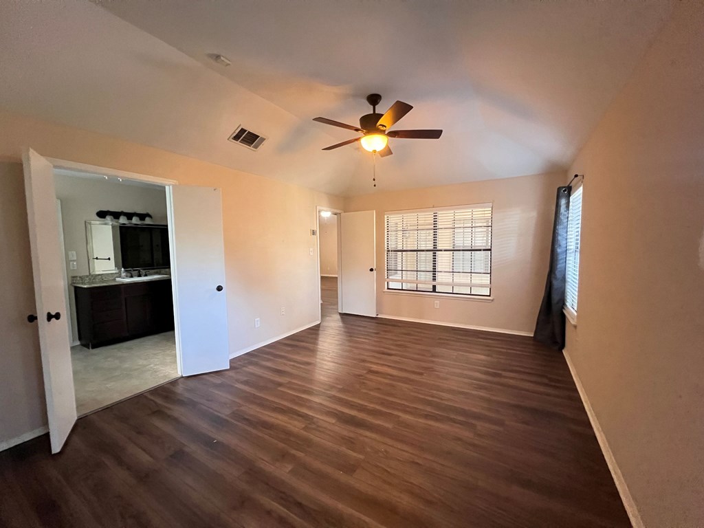 A room with a ceiling fan and wooden flooring.