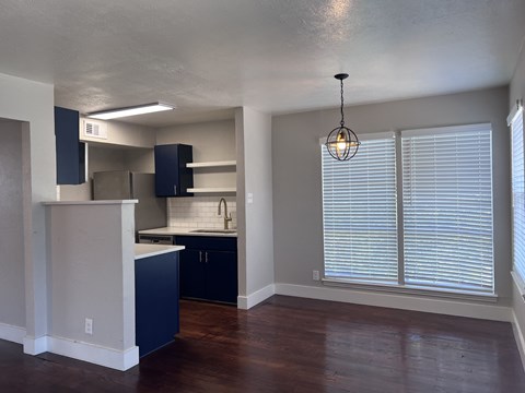 an empty living room with a large window and a kitchen
