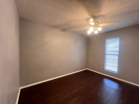 A room with a ceiling fan and wooden flooring.