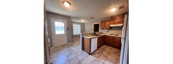 A kitchen with a white fridge and wooden cabinets.