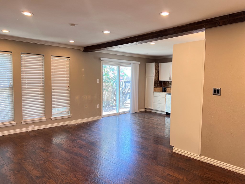 A room with wooden floors and a sliding glass door leading to a balcony.