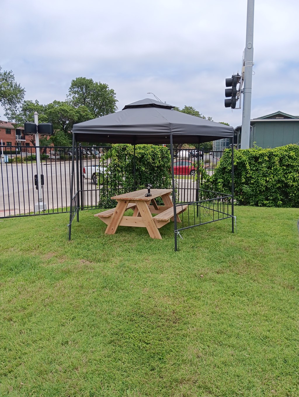 A picnic table is set up under a canopy in a grassy area.