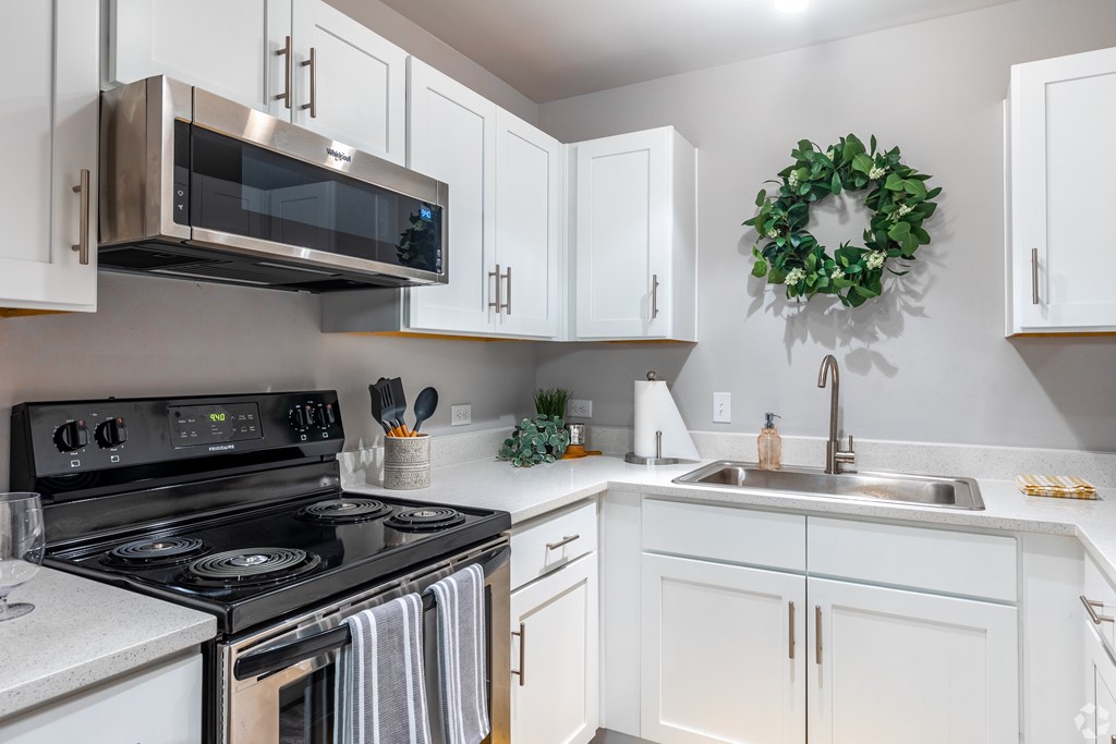 A kitchen with a stove, microwave, and a wreath on the wall.
