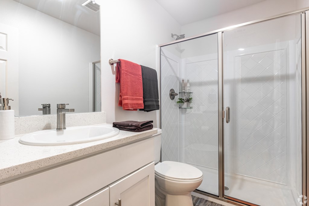 A white bathroom with a toilet, sink, and shower.