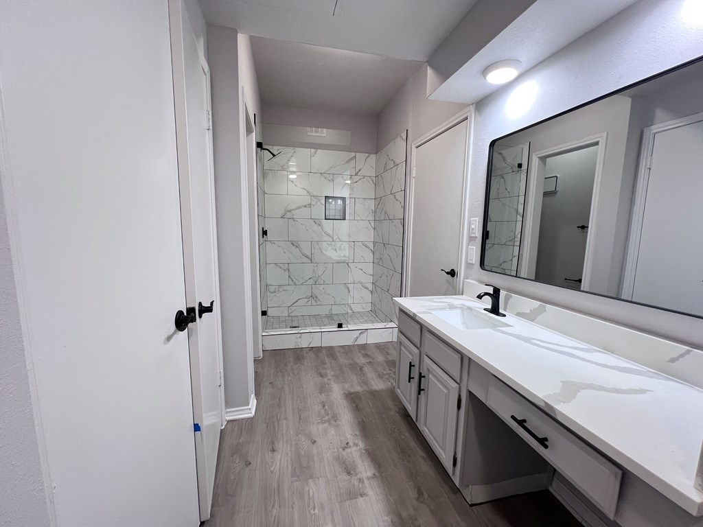 A bathroom with a white sink and a marble tile shower.